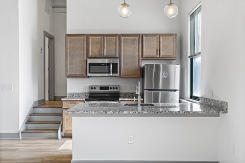 A kitchen with a stainless steel refrigerator, microwave, and oven.