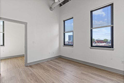 A room with a white wall and a window with blinds.