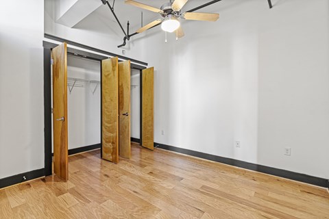 A room with a ceiling fan and wooden floors.
