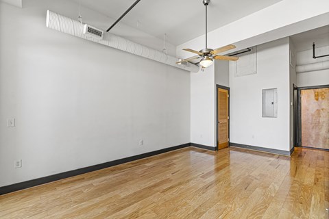 A room with a ceiling fan and a light on the wall.