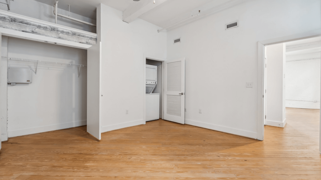 A large empty room with wooden floors and white walls.