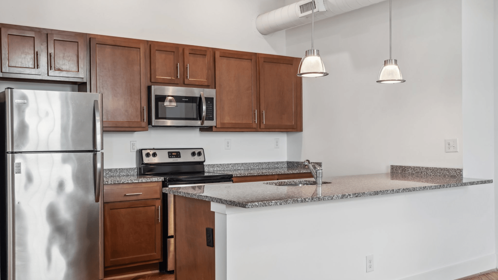 A kitchen with a stainless steel refrigerator, microwave, and oven.