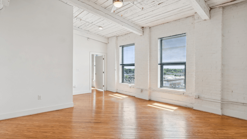 A large empty room with wooden floors and white walls.