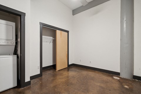 A room with a brown floor and a white wall with a door open.