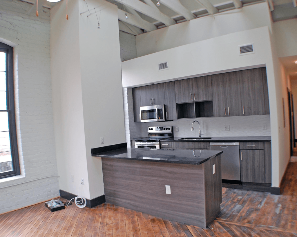 A kitchen island with a black countertop and wooden cabinets.