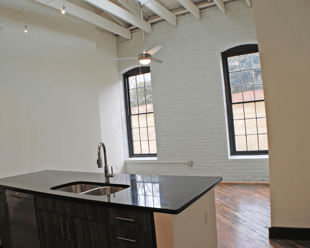 A kitchen with a black counter top and a window.