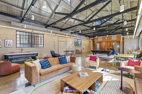 A large, open-plan living area with a variety of seating options and a high ceiling with exposed beams.