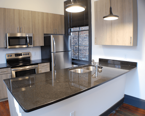 A kitchen with a granite counter top and stainless steel appliances.