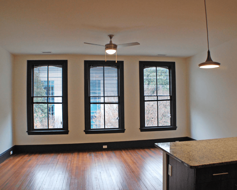 A room with a ceiling fan and three windows.