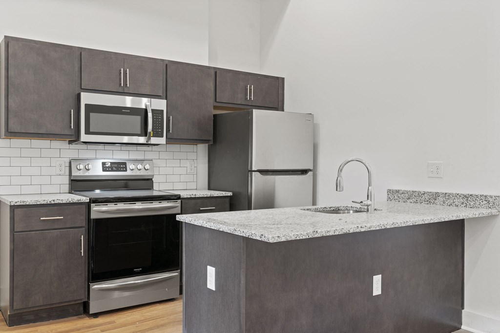 Kitchen space with stainless steel fridge, stove, microwave, dishwasher, and sink