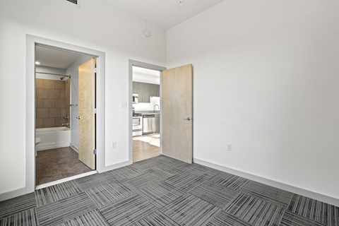 A room with a carpeted floor and two open doors.