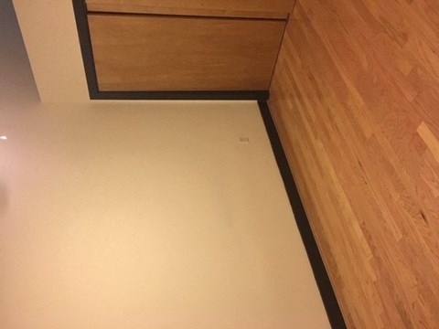 A white countertop with a wooden cabinet above it.