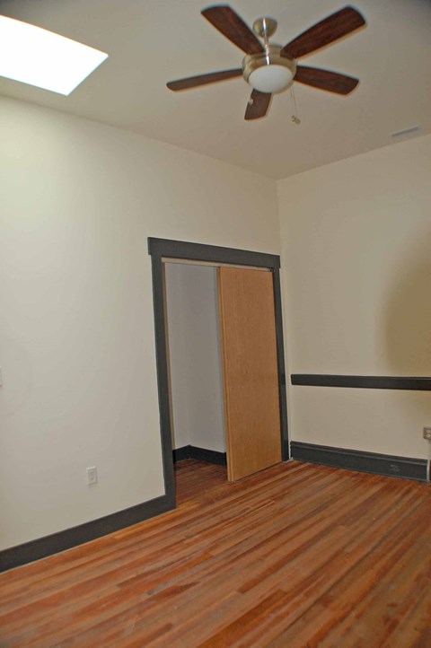 A room with a ceiling fan and a wooden floor.