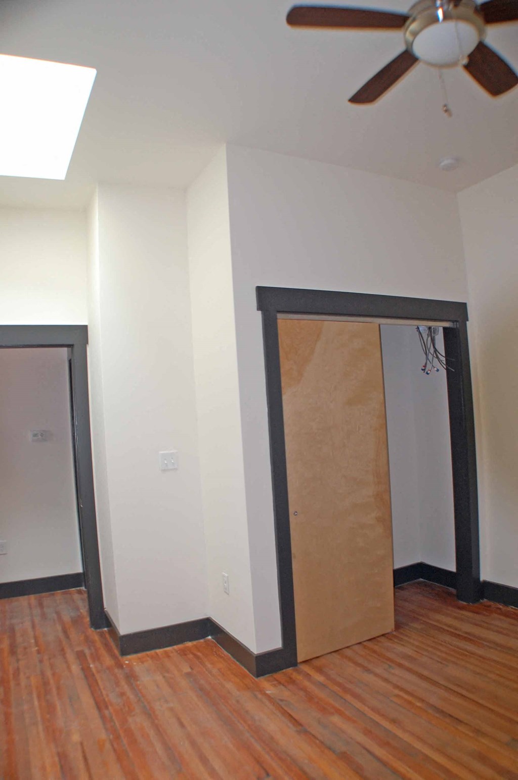 A room with a ceiling fan and a doorway covered in cardboard.