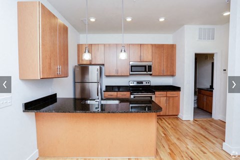 A kitchen with wooden cabinets and black countertops.