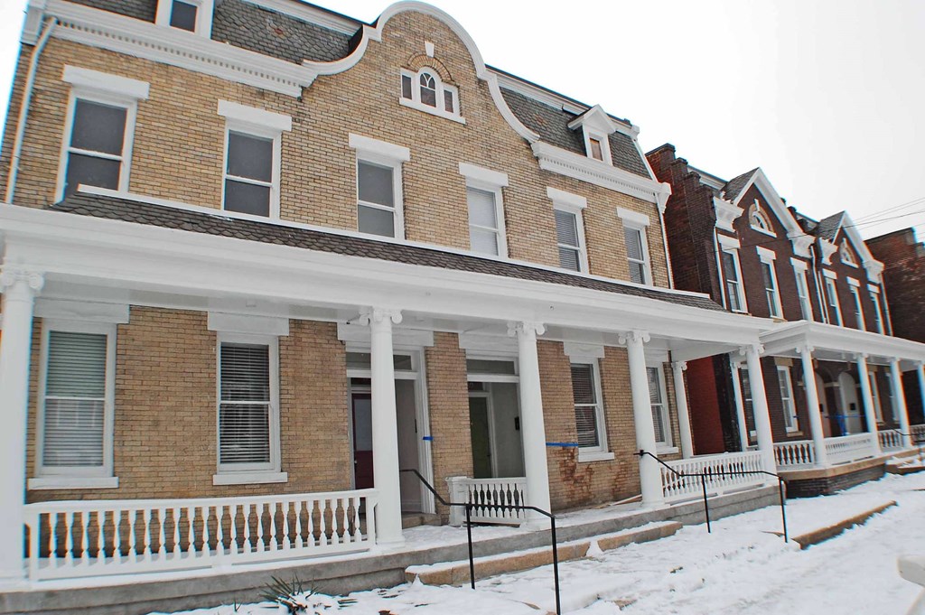 A row of Victorian style houses with snow on the ground.