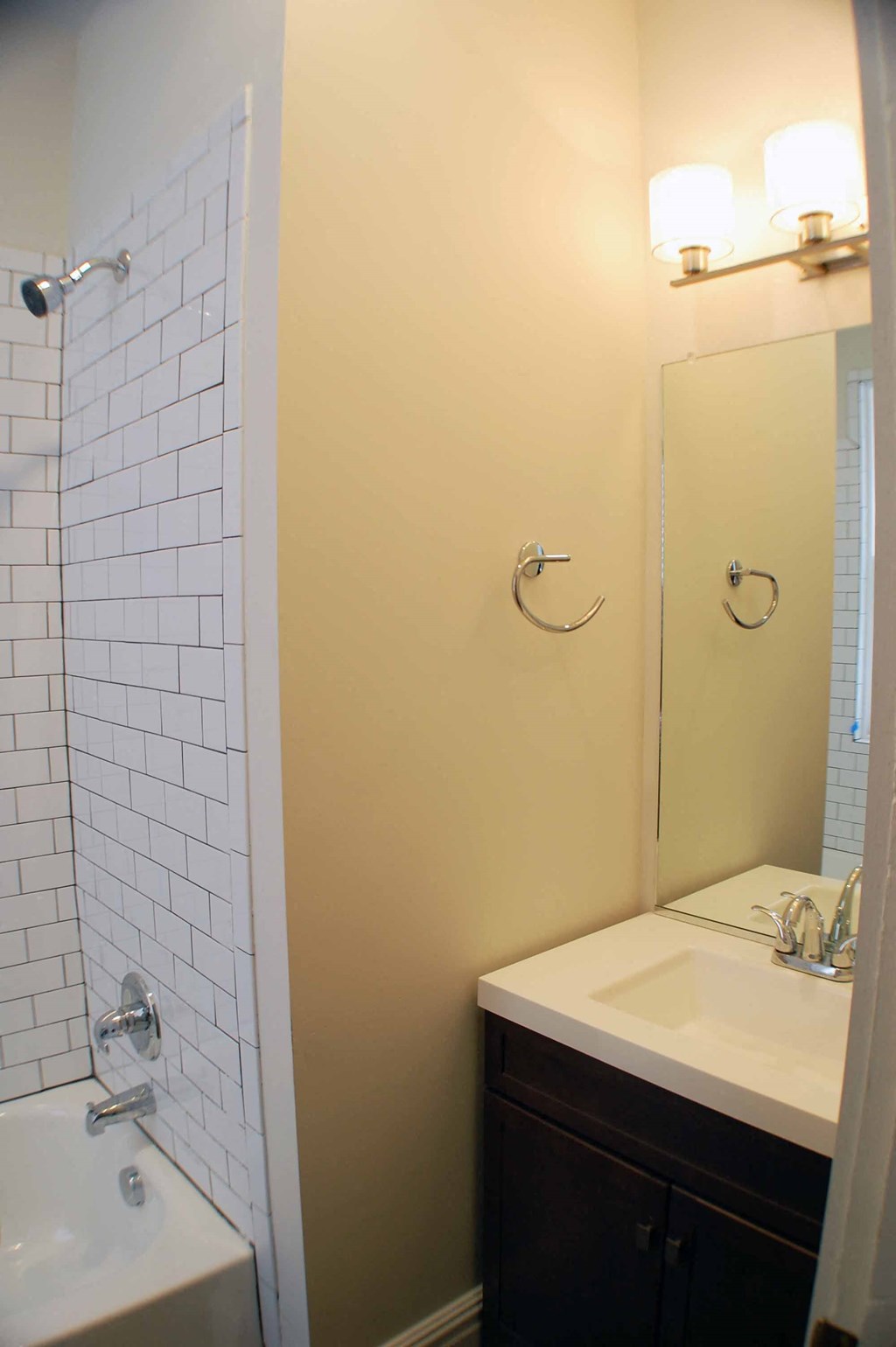 A white tiled shower next to a sink in a bathroom.