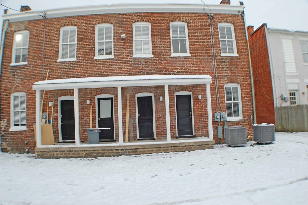 A red brick house with a white door and windows.