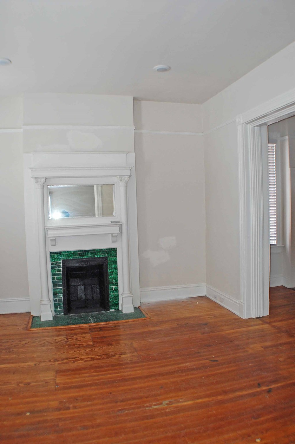 A fireplace with a green border sits in a room with wooden floors.