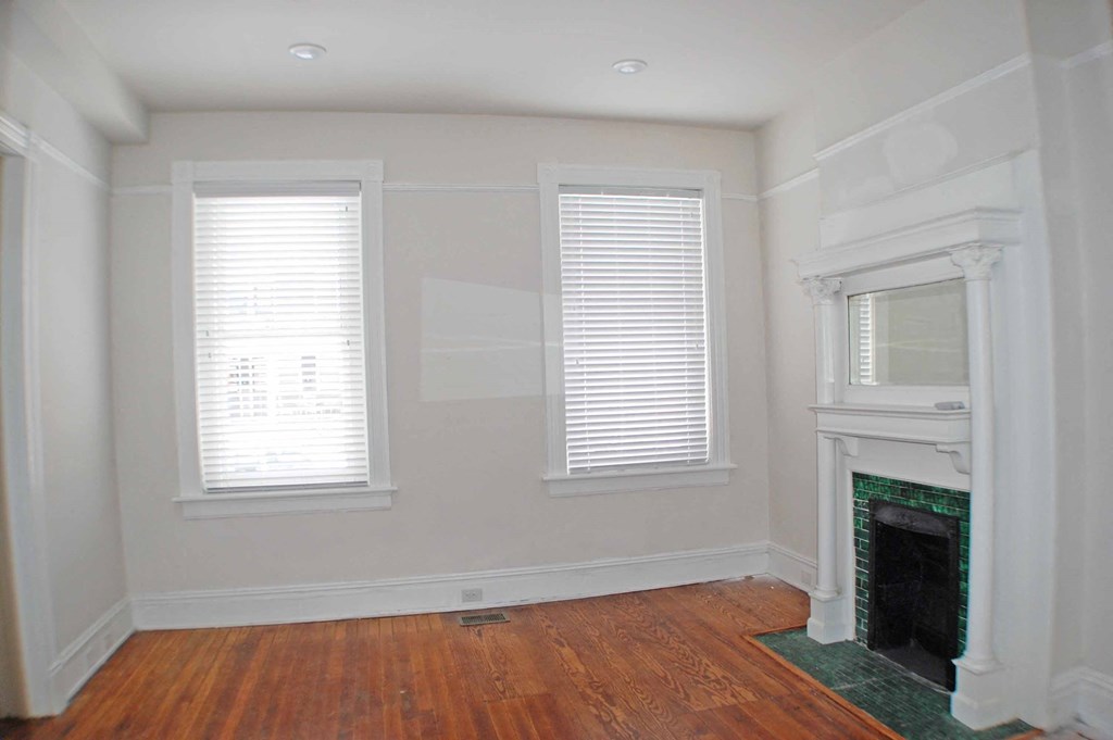 A room with a fireplace and two windows.