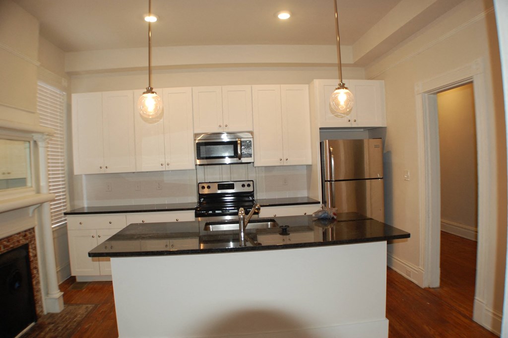 A kitchen with white cabinets and a black countertop.