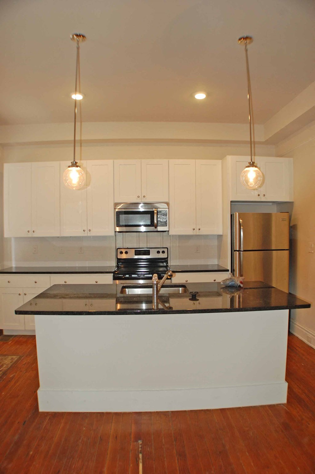 A kitchen with a black counter top and white cabinets.