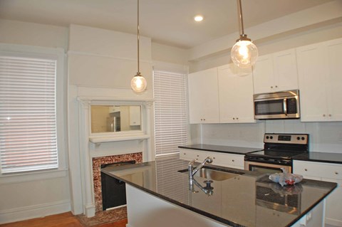 A kitchen with a black counter top and white cabinets.
