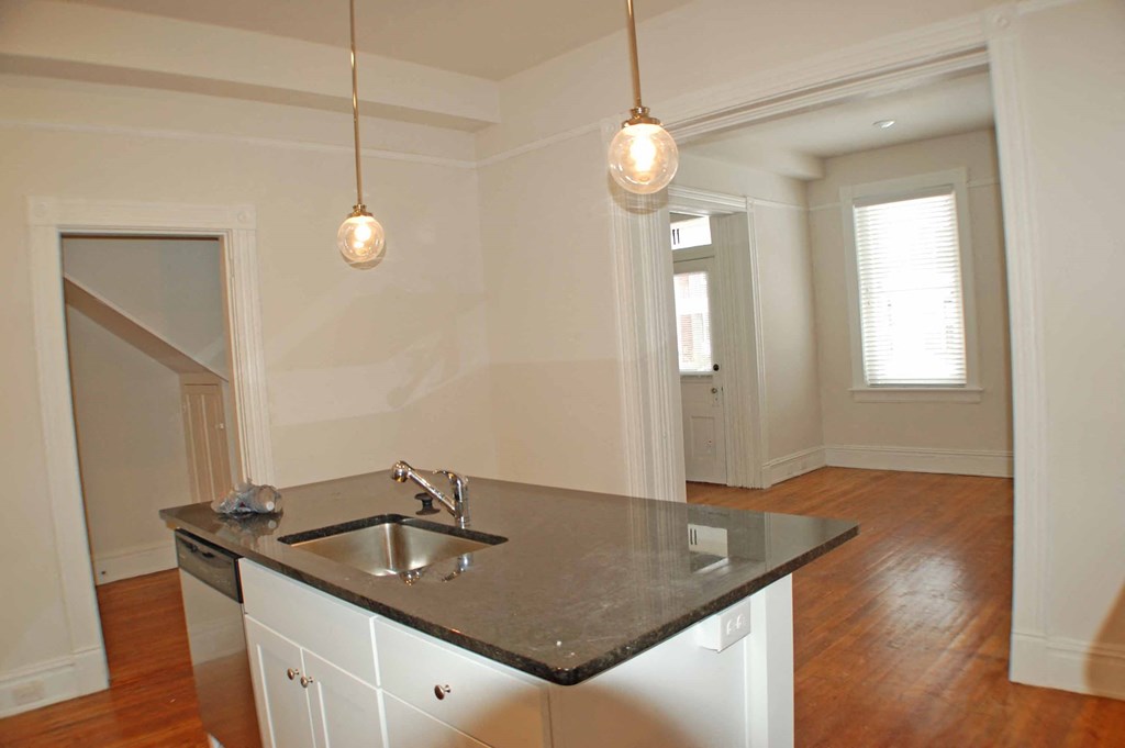 A kitchen with a black counter top and white cabinets.