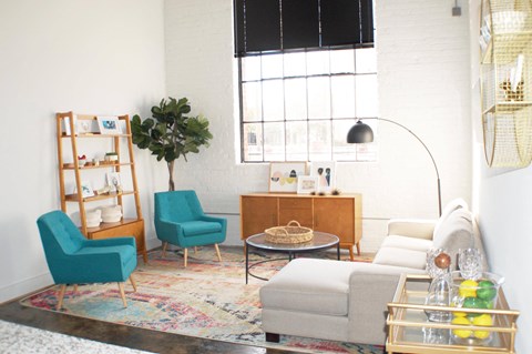 A living room with a blue chair and a wooden cabinet.
