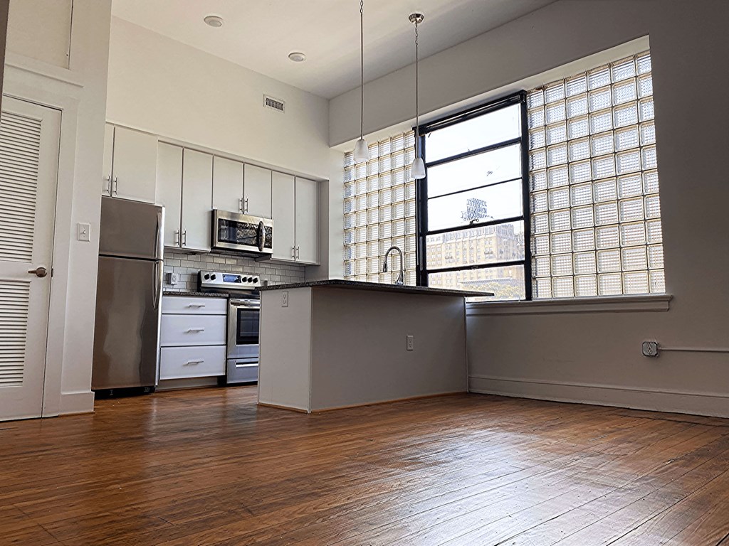 A kitchen with wooden floors and a window with blinds.