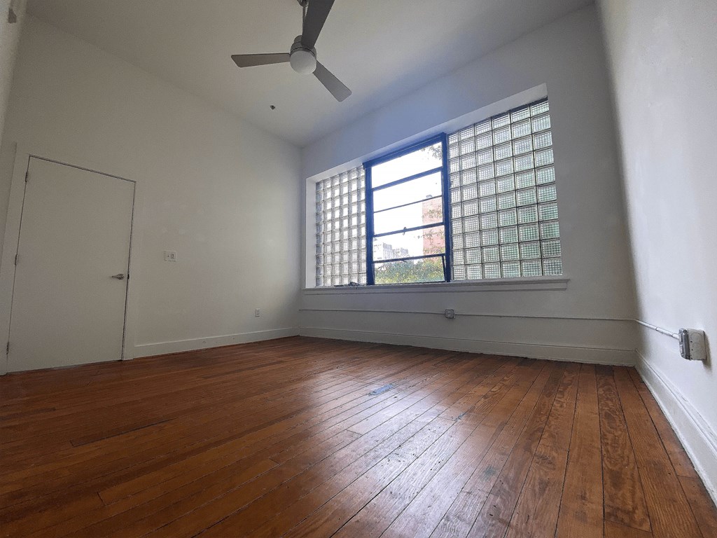 A room with a wooden floor and a window with a blue frame.