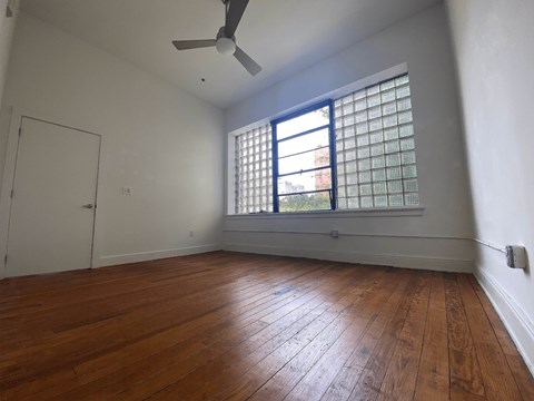 A room with a wooden floor and a window with a blue frame.