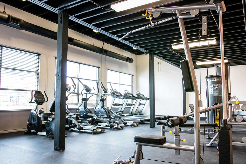 A gym with a variety of equipment including treadmills, weights, and exercise machines.