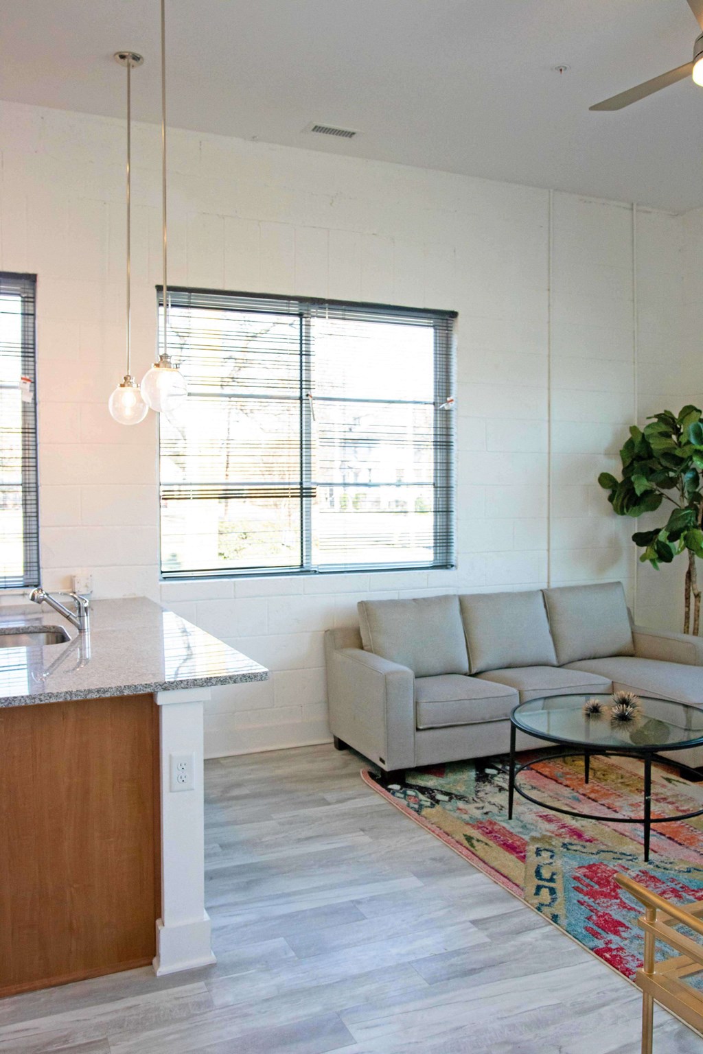 A modern kitchen with a wooden island and a grey couch.