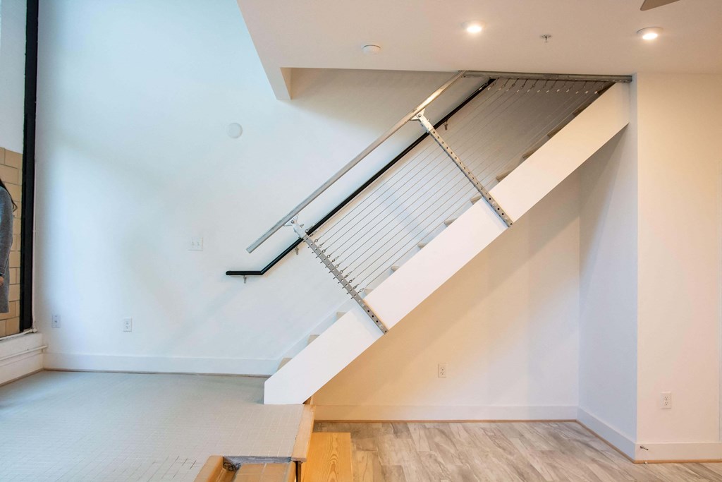 A white staircase with a metal railing and wooden steps.