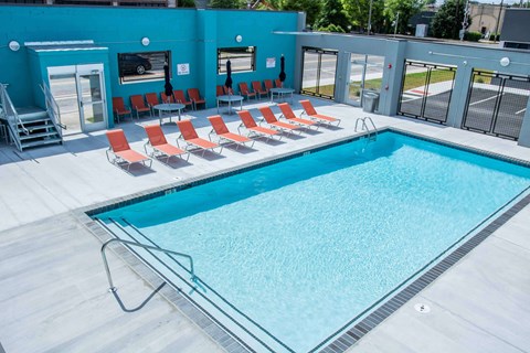 A swimming pool with red chairs around it.