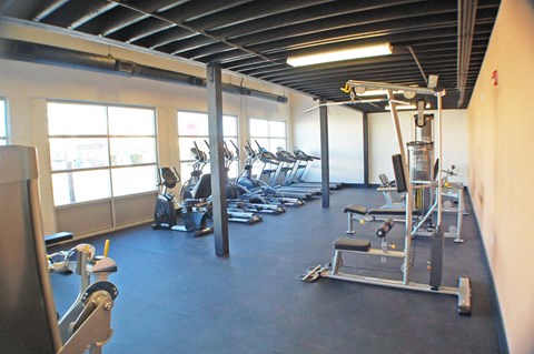 A gym with a variety of equipment including treadmills, weights, and exercise machines.