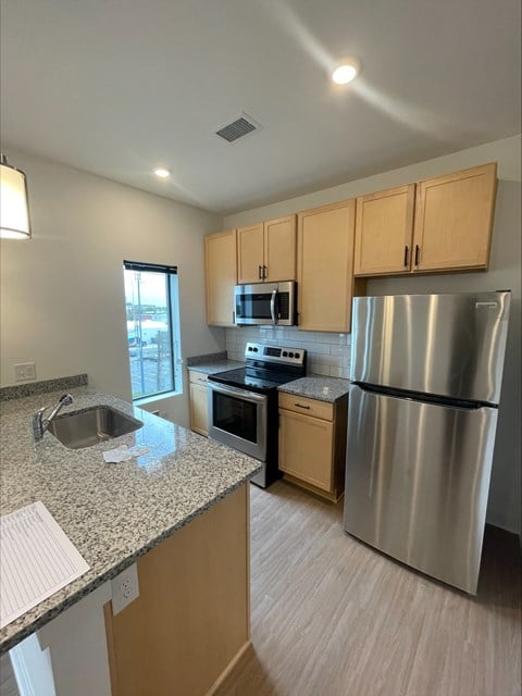 an empty kitchen with stainless steel appliances and granite counter tops