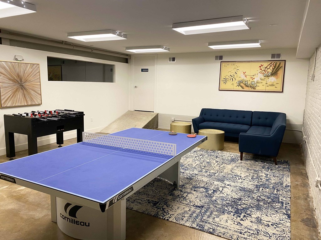 a game room with a blue ping pong table and a blue couch