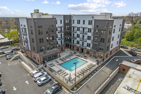 An aerial view of a multi-story apartment complex with a pool.