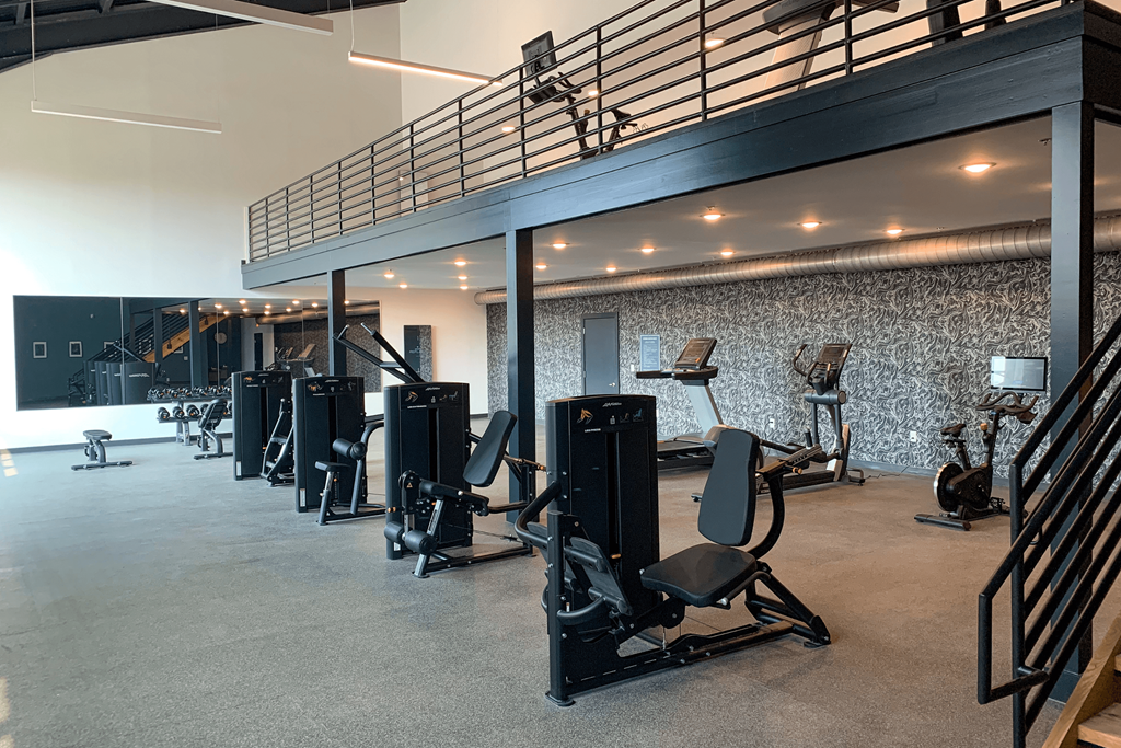 a large fitness room with weights and cardio equipment