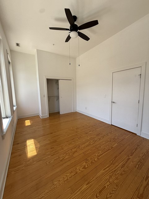 A room with a ceiling fan and wooden flooring.
