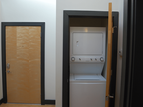 A small white washing machine is in a doorway.