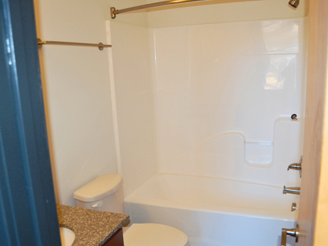 A white toilet sits next to a white bathtub in a bathroom.