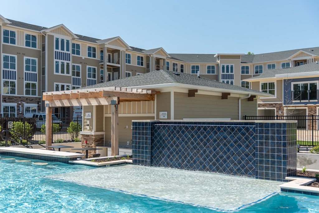 a large swimming pool with a gazebo in front of an apartment building