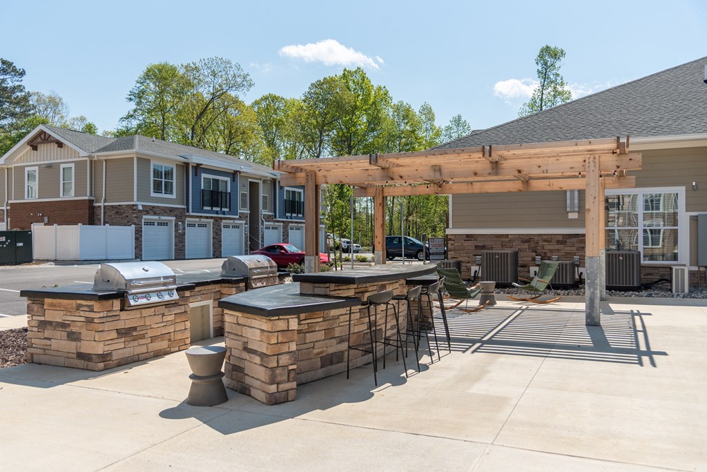 a patio with a bar and a grill in front of a house