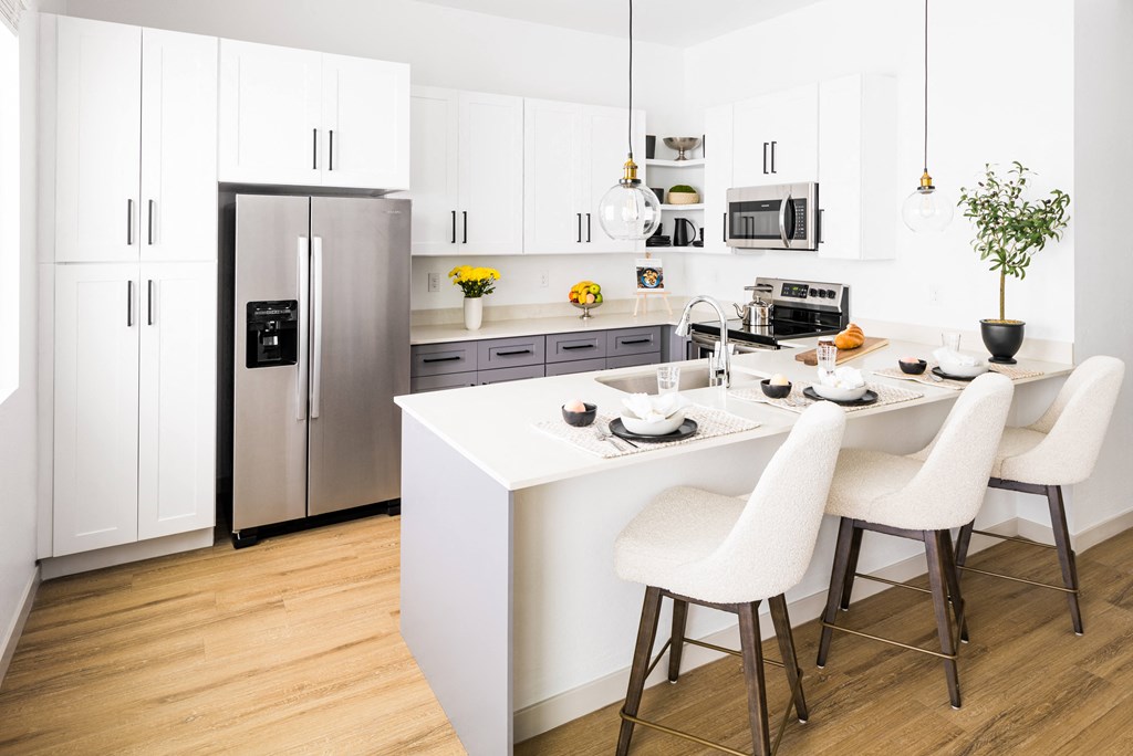 a kitchen with white cabinets and a white island with white chairs
