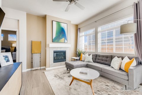 A living room with a grey couch, a white coffee table, and a painting on the wall.