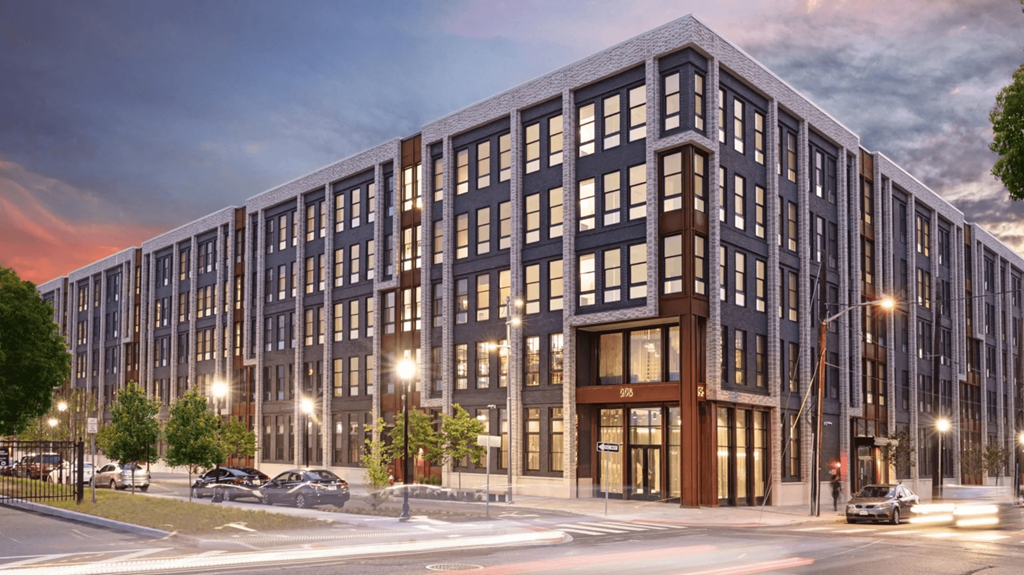 A modern multi-story building with a parking lot in front.