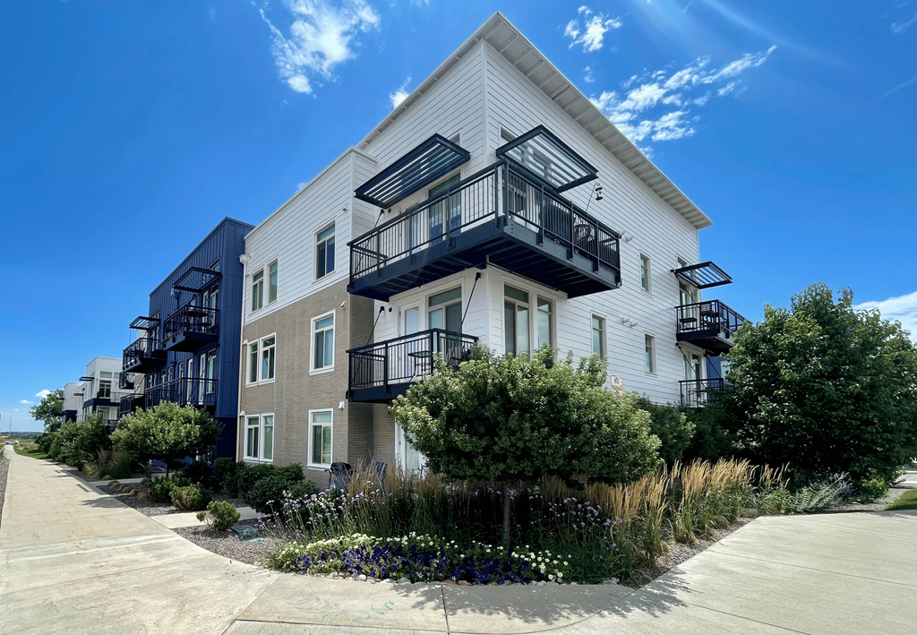 a white building with three balconies and a garden in front of it
